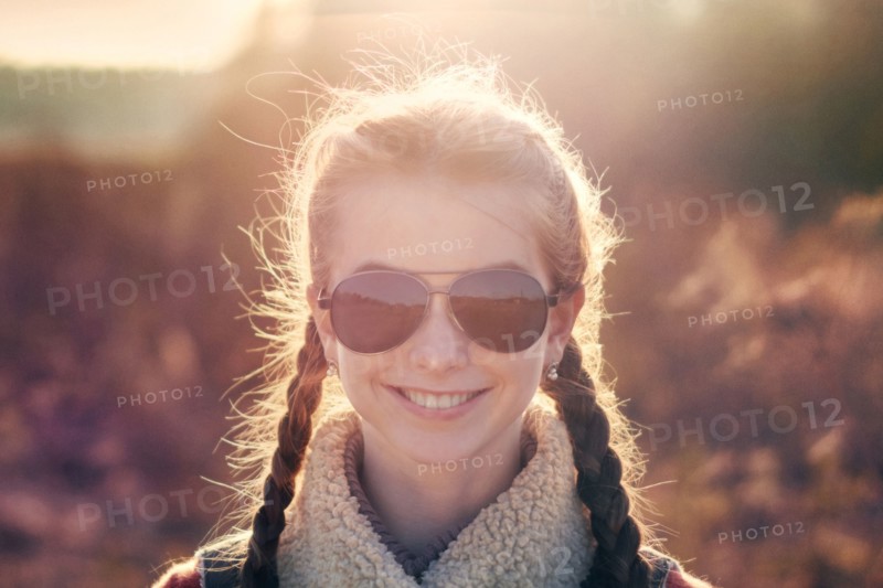 Caucasian teenage girl wearing sunglasses in field