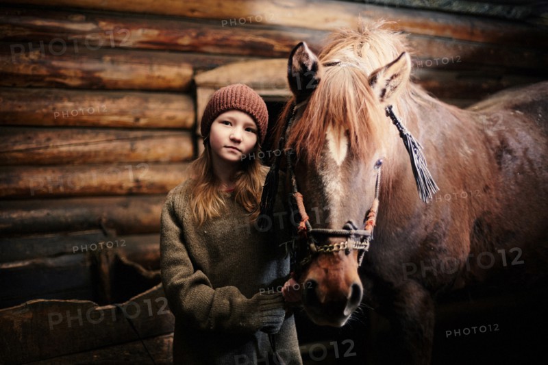 Caucasian teenage girl standing with horse in barn
