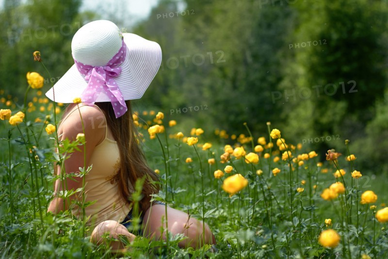 Caucasian teenage girl sitting in field with flowers
