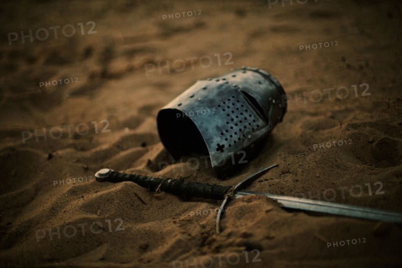 Medieval helmet and sword in sand