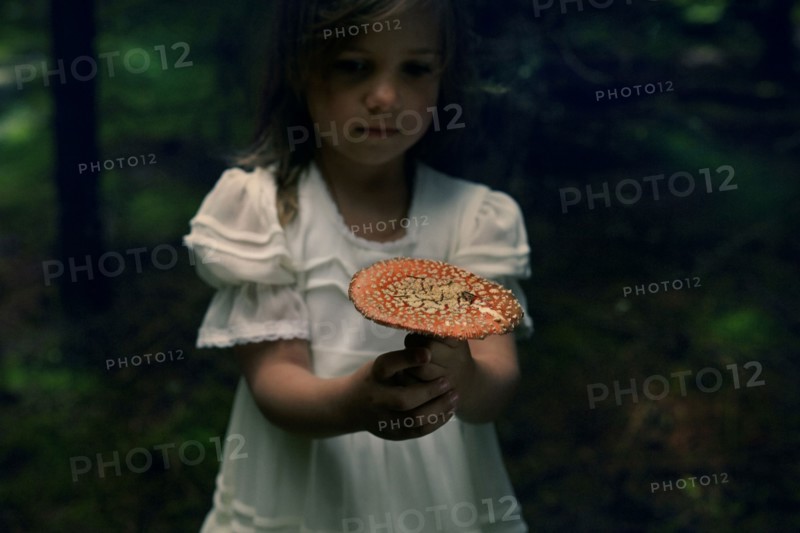 Caucasian girl holding mushroom in forest