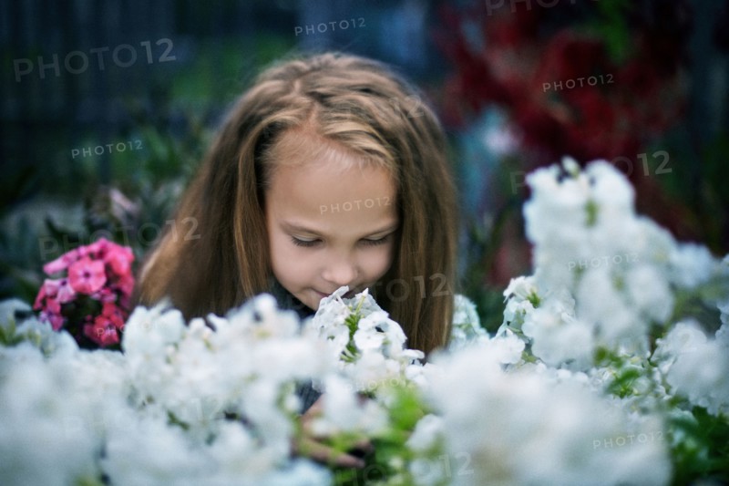 Caucasian girl smelling flowers in garden