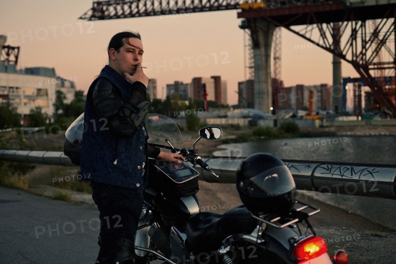 Caucasian man smoking near motorcycle