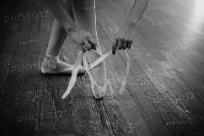 Caucasian ballerina tying pointe shoes
