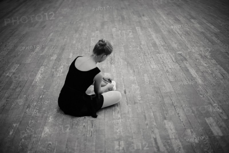 Caucasian ballerina tying pointe shoes