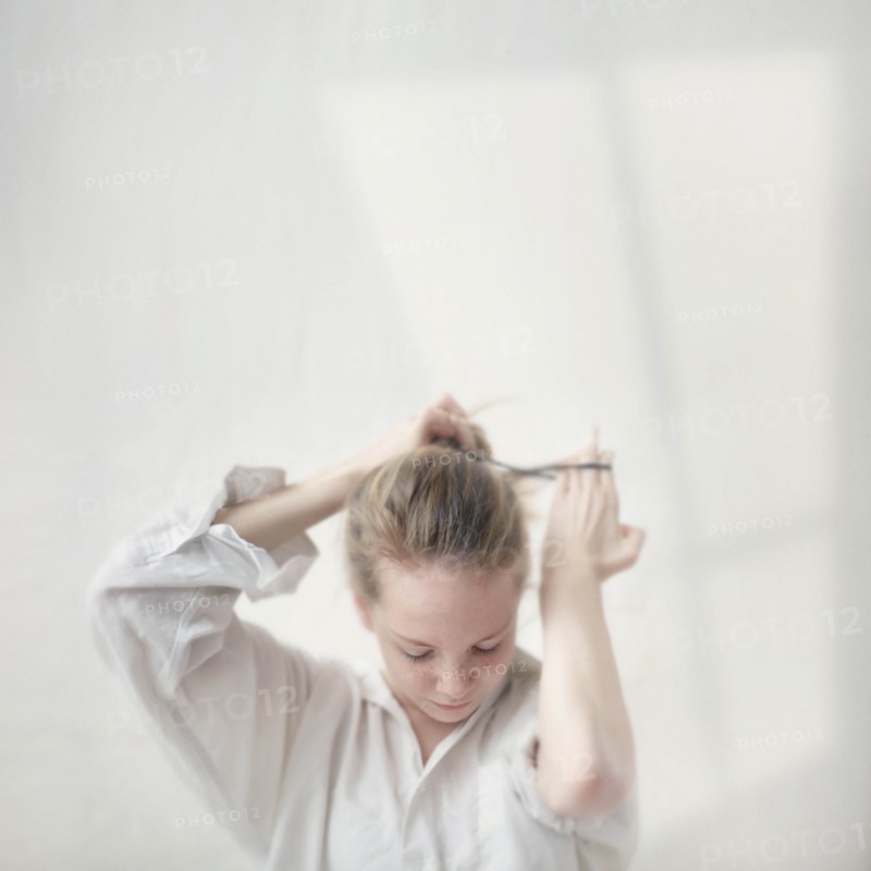 Caucasian teenage girl tying her hair into bun