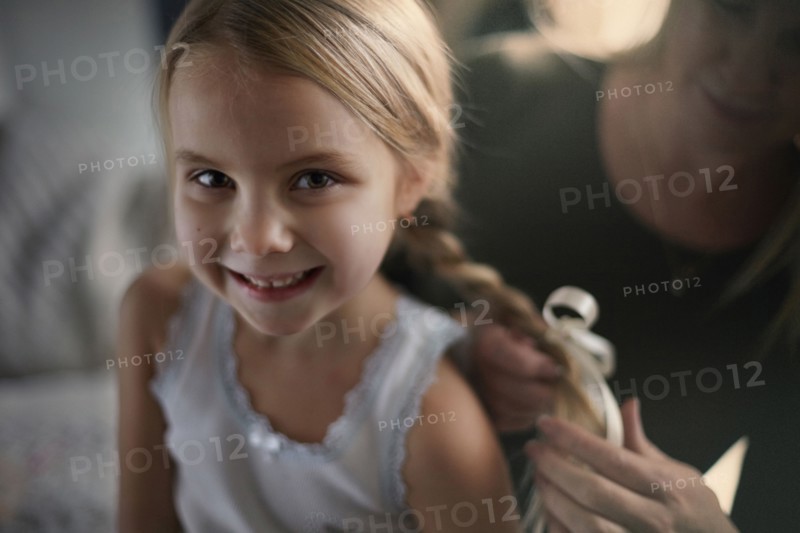 Mother braiding hair of daughter