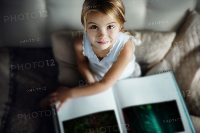 Caucasian girl reading book on sofa