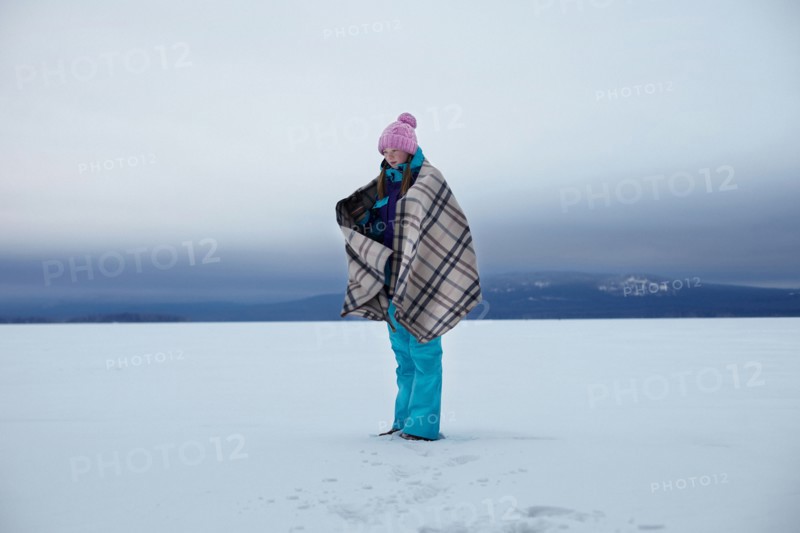 Caucasian teenage girl wrapped in blanket in snow