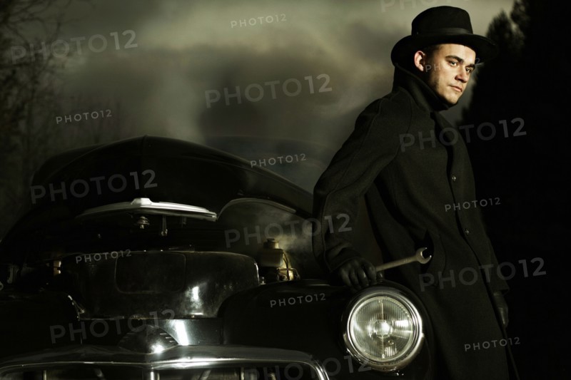 Caucasian man working on broken-down vintage car