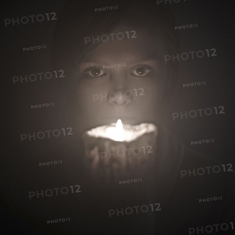 Caucasian woman holding candle near face