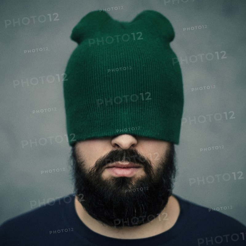 Caucasian man wearing beanie hat over eyes