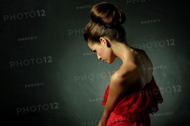 Caucasian woman wearing red evening gown and hair bun