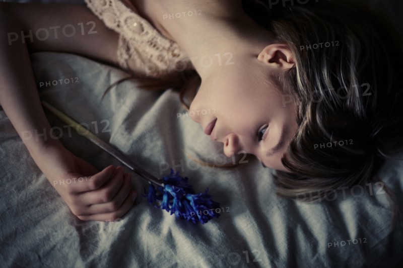 Caucasian teenage girl holding flower on bed