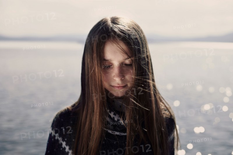 Pensive Caucasian girl at lake