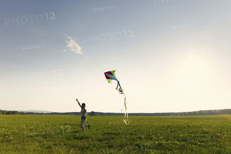 Caucasian girl running in field flying kite