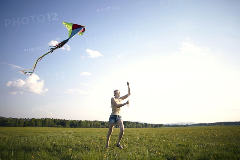 Caucasian girl running in field flying kite