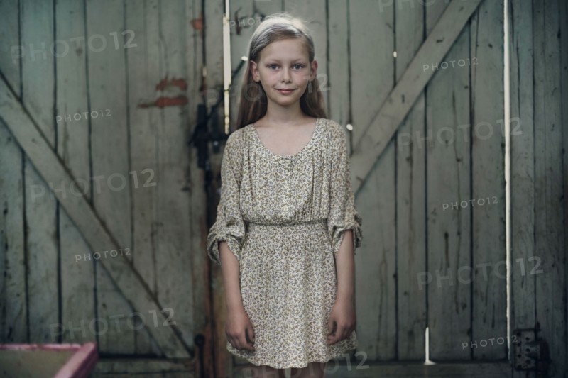 Caucasian girl wearing dress standing in barn