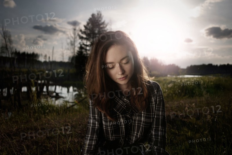 Pensive Caucasian woman in field near lake