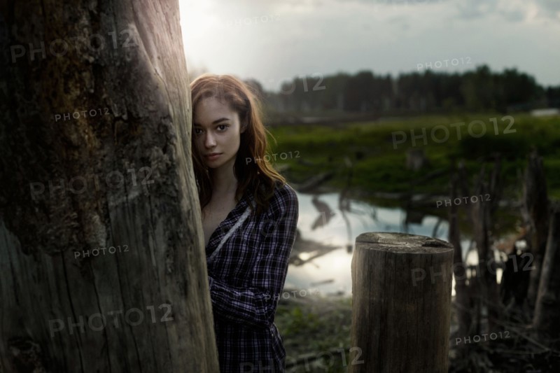 Pensive Caucasian girl leaning on wooden pillar