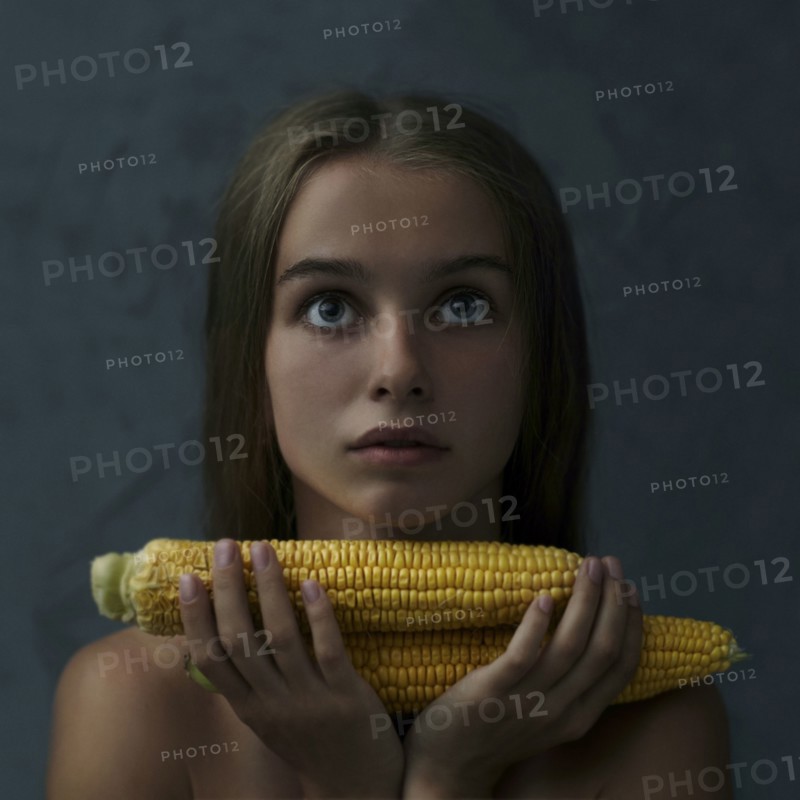 Caucasian girl holding corn on cob and looking up