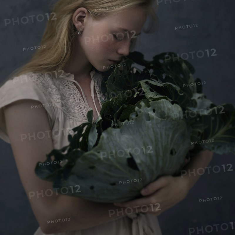 Caucasian girl smelling leafy green lettuce