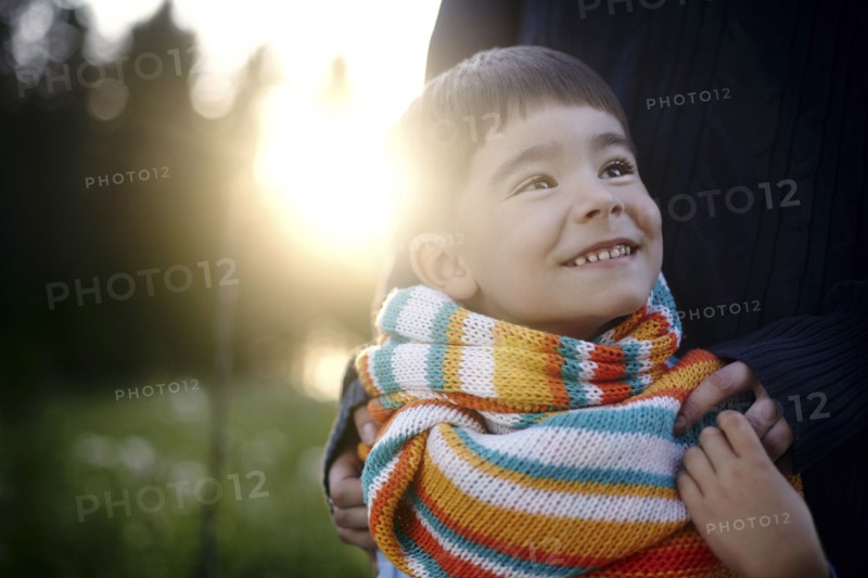 Caucasian woman holding shoulders of boy wearing multicolor scarf
