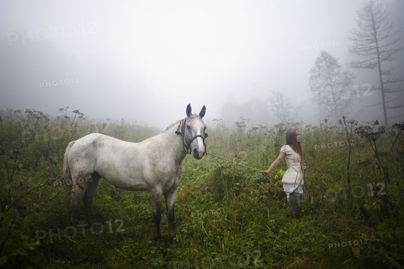 Caucasian girl walking horse in foggy field