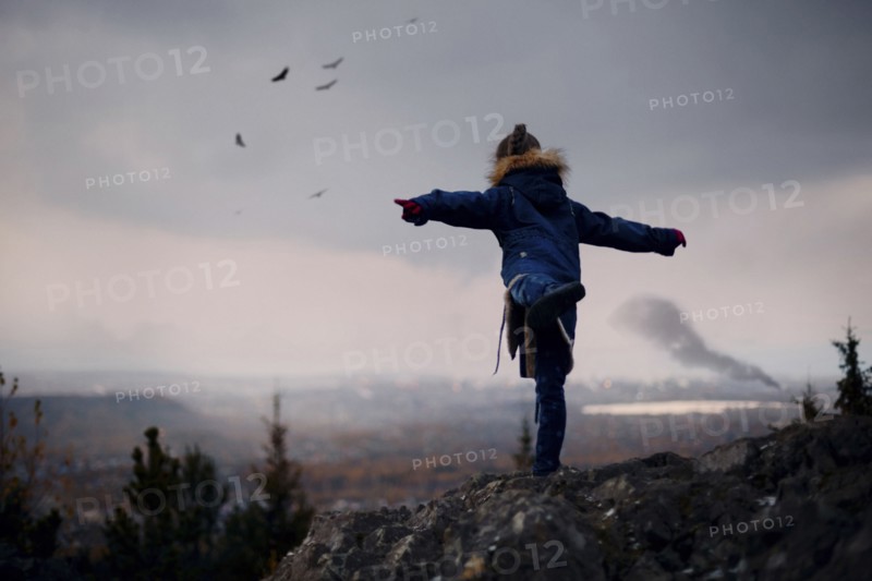 Caucasian girl balancing on rocks imitating flying birds
