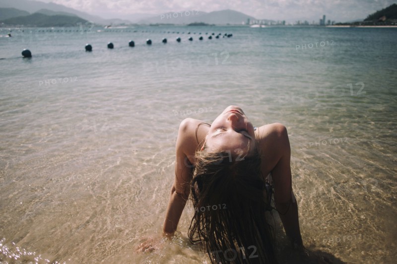 Caucasian woman wearing bikini sitting in waves on beach
