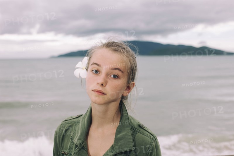 Caucasian woman with flower in hair near ocean