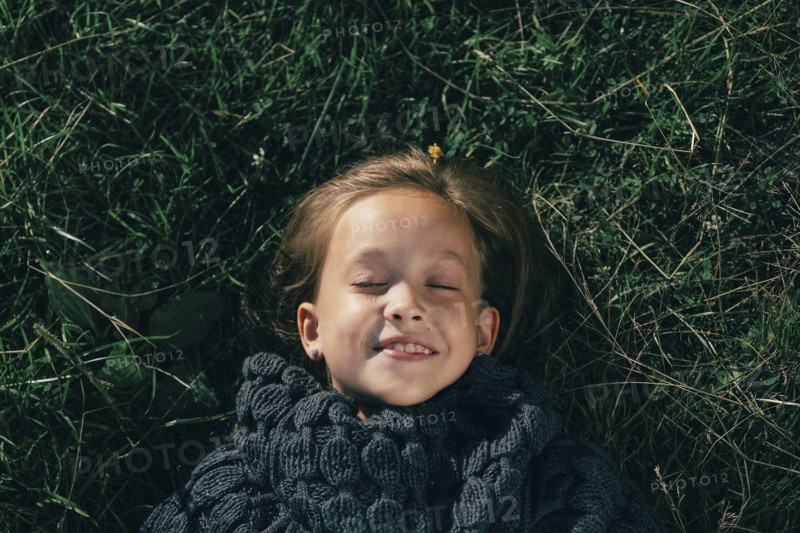 Caucasian girl wearing sweater laying in grass