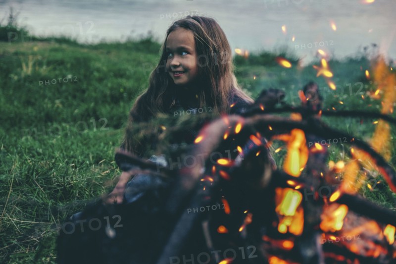 Caucasian girl sitting near campfire