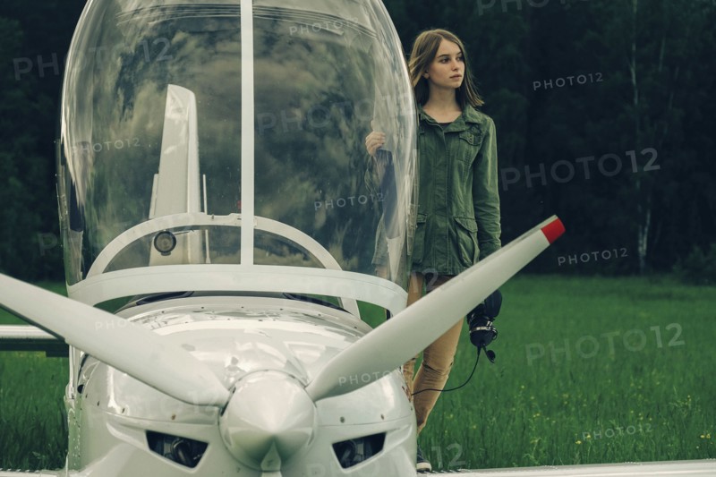Caucasian woman standing near an airplane cockpit