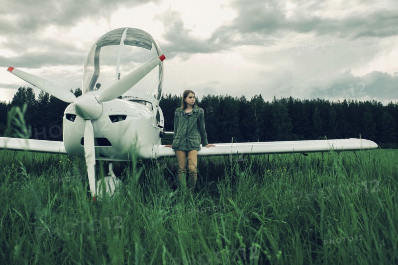 Caucasian woman leaning on airplane wing