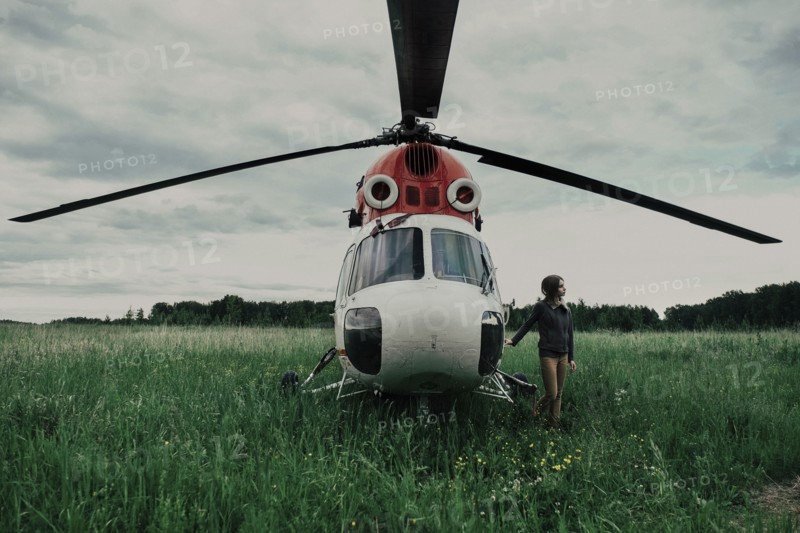 Caucasian woman standing near helicopter in field
