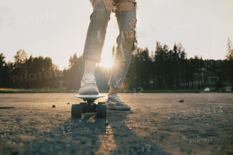 Legs of Caucasian teenage girl standing on skateboard