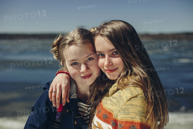 Caucasian sisters hugging on beach