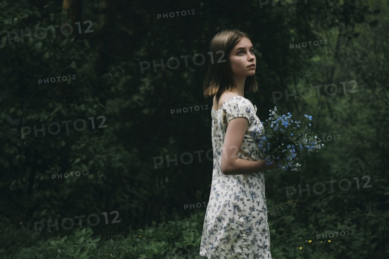 Caucasian woman holding flowers in forest
