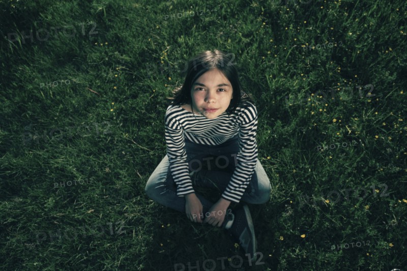 Smiling Caucasian teenage girl sitting in grass