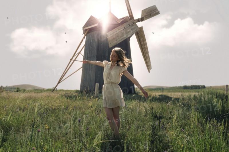 Caucasian woman balancing in grass near windmill