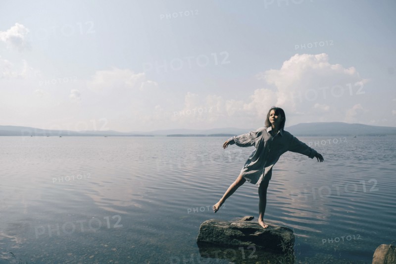 Caucasian girl standing on rock in lake