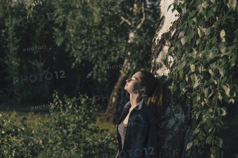 Caucasian woman leaning on tree trunk