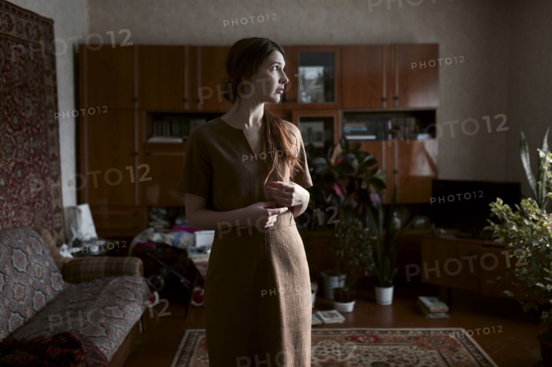 Pensive Caucasian woman standing in livingroom