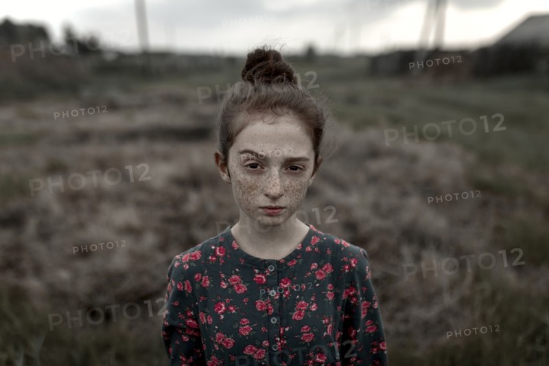 Caucasian girl with freckles raising eyebrow in field
