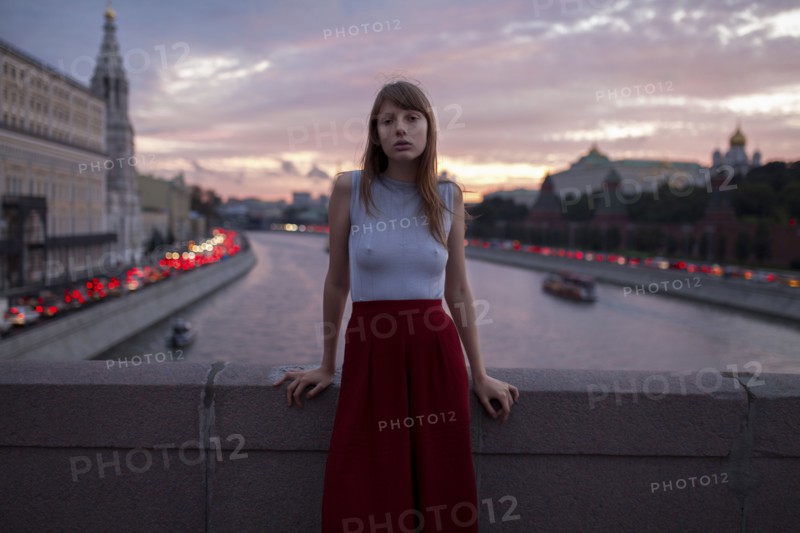 Caucasian woman leaning on bridge over urban canal