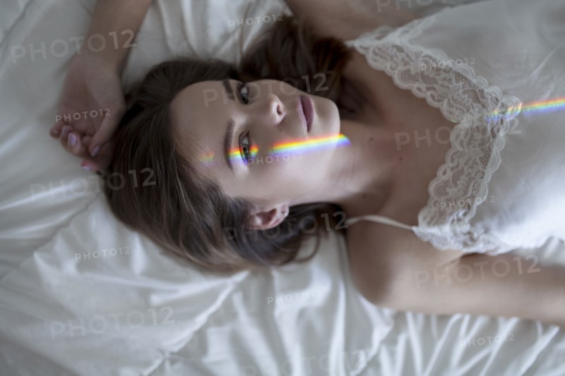 Caucasian woman laying on bed wearing nightgown