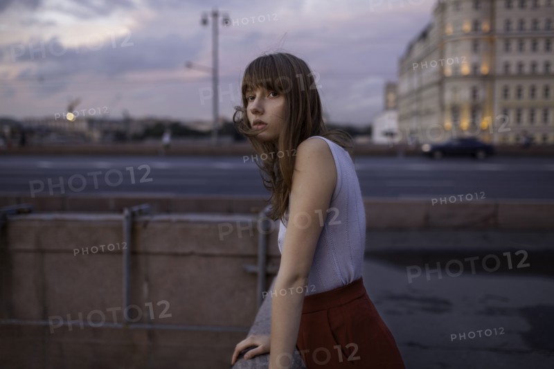 Serious Caucasian woman leaning on wall in city