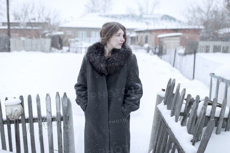 Caucasian woman wearing coat in winter near fence