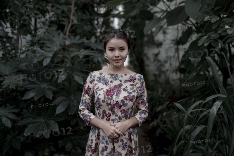 Asian woman smiling near foliage